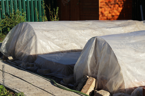 Vegetable patches with seedlings covered with spunbond and polyethylene film to keep humidity and against ground frost in the spring garden
