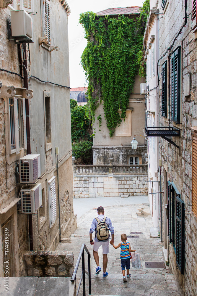 Father and son walking through little town street.