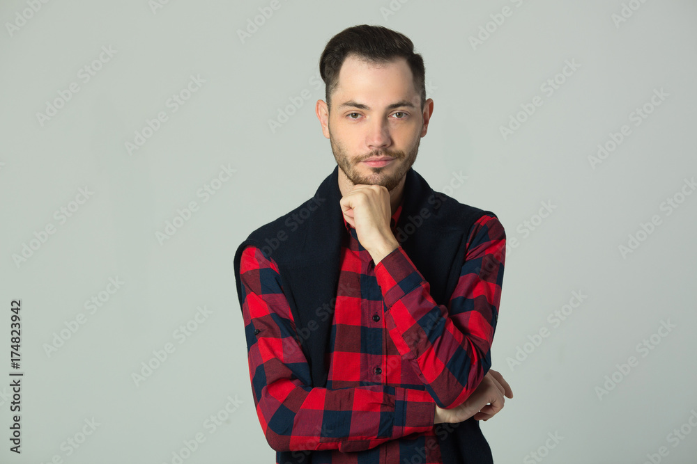 handsome young guy in checkered shirt in studio on wall background handsome young guy in checkered shirt in studio on wall background