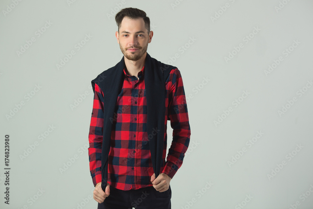 handsome young guy in checkered shirt in studio on wall background handsome young guy in checkered shirt in studio on wall background