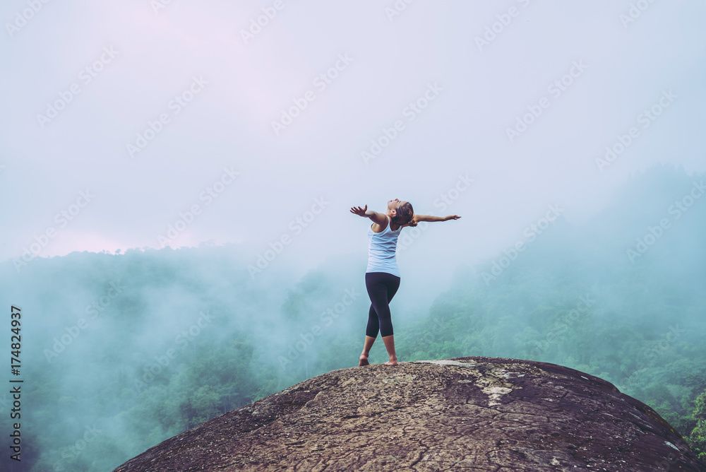 Obraz premium Asian women travel relax in the holiday. Stand on a rocky cliff. Wild nature wood on the mountain.
