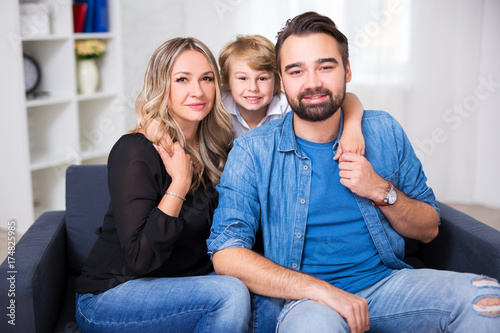 happy family portrait - young couple and little son sitting on sofa