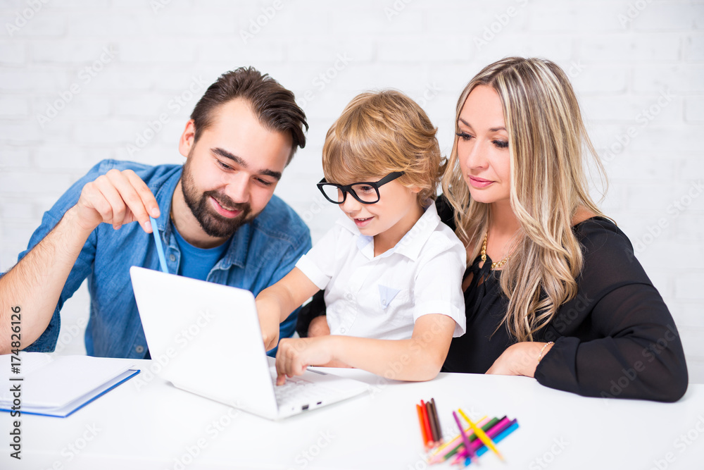 happy cute little school boy in glasses doing homework with parents happy cute little school boy in glasses doing homework with parents