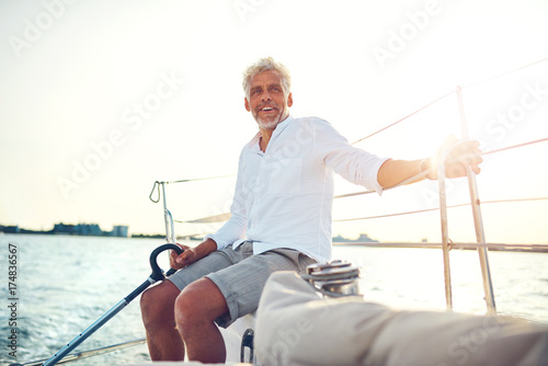 Smiling mature man sitting on the deck of a sailboat