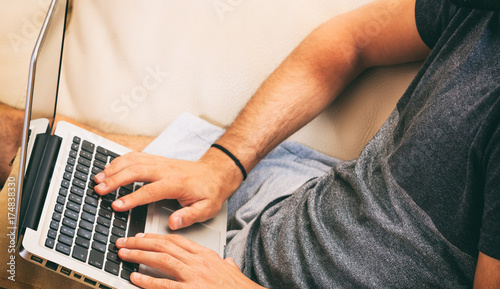 Man working with a laptop sitting on a sofa at home