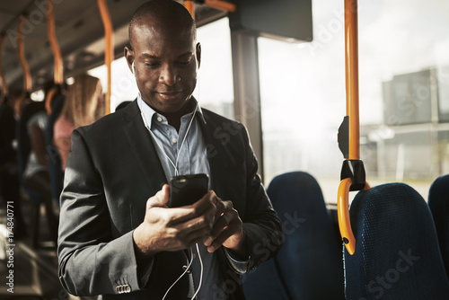 Smiling African businessman listening to music during his morning commute photo