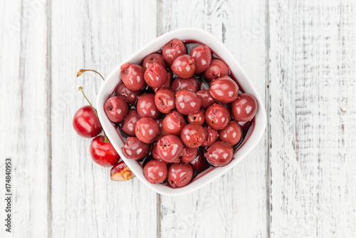 Portion of Canned Cherries on wooden background, selective focus