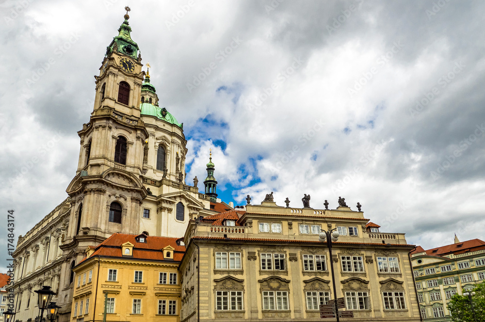 Baroque church of St. Nicholas in Malá Strana quarter in the romantic Prague under blue sky. Panoramic of the old city of the hundred towers on a summer day in the capital of the Czech Republic. 