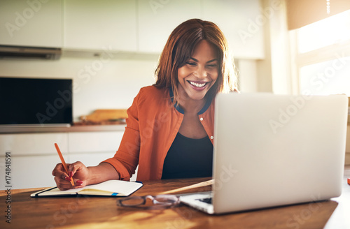 Smiling young female entrepreneur working online at her kitchen