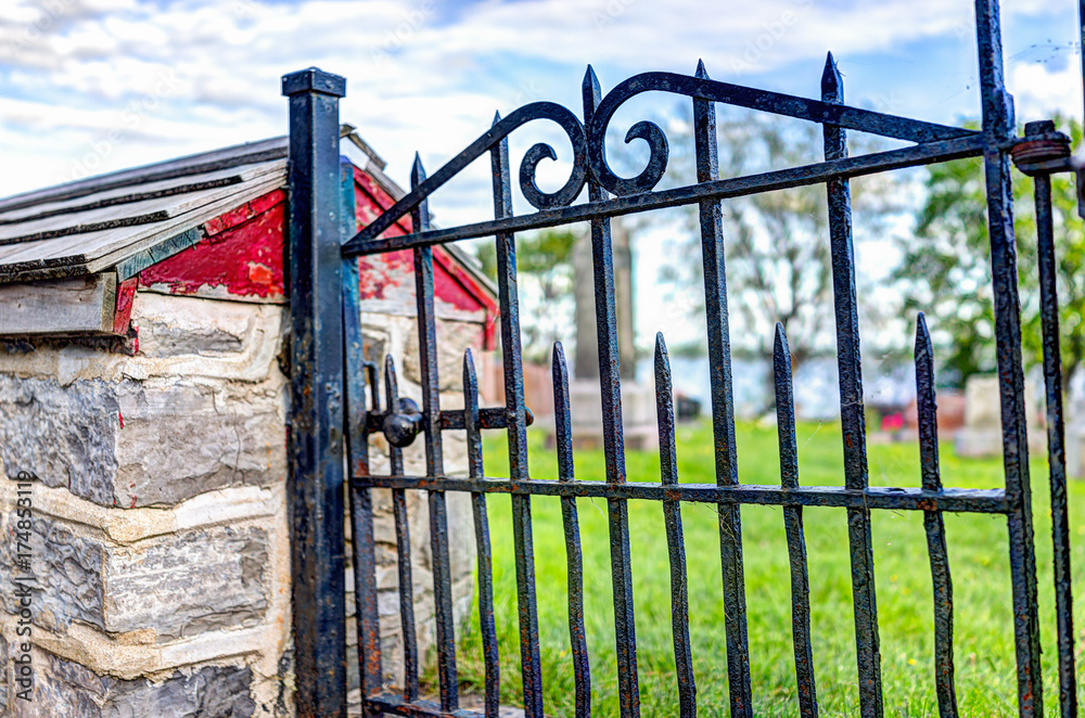 Closeup of small red metal gate to cemetary by church in summer in Europe