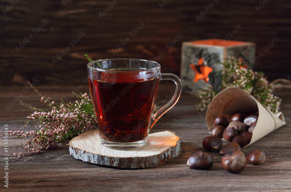 still life with a cup of tea, a bag of chestnuts, candle and heather on a dark wooden background still life with a cup of tea, a bag of chestnuts, candle and heather on a dark wooden background