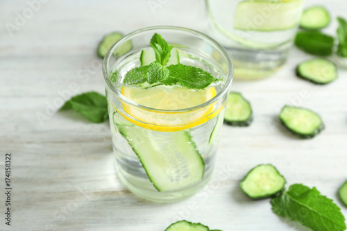 Glass of fresh cucumber water with lemon and mint on table