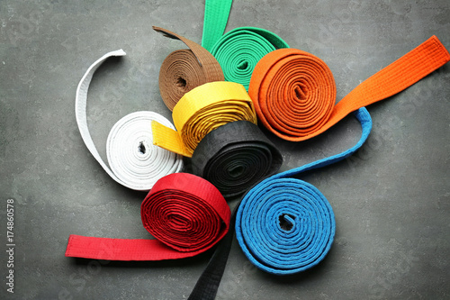 Colorful karate belts on grey background photo