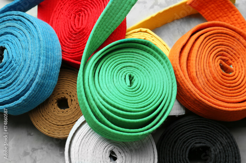 Colorful karate belts on grey background