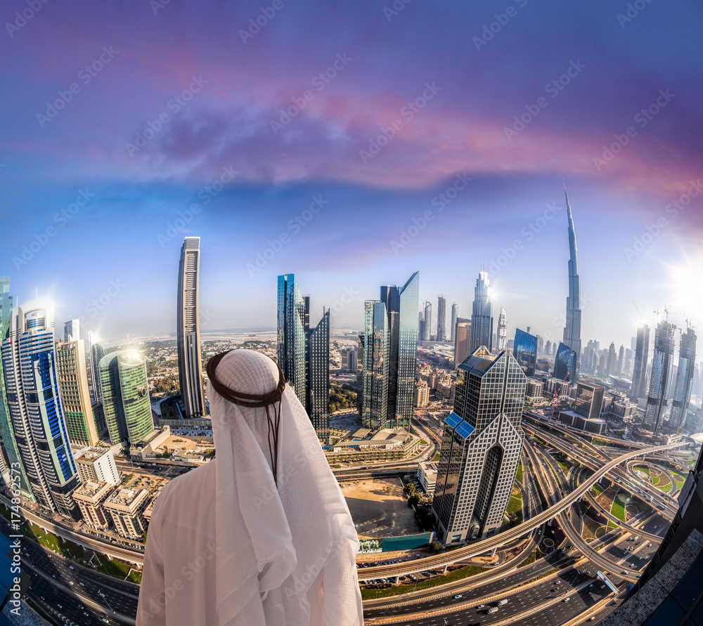 Obraz premium Arabian man watching cityscape of Dubai with modern futuristic architecture in United Arab Emirates.