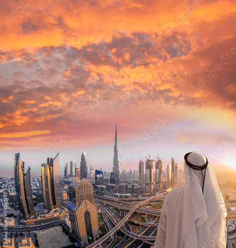 Arabian man watching cityscape of Dubai with modern futuristic architecture in United Arab Emirates. © Tomas Marek