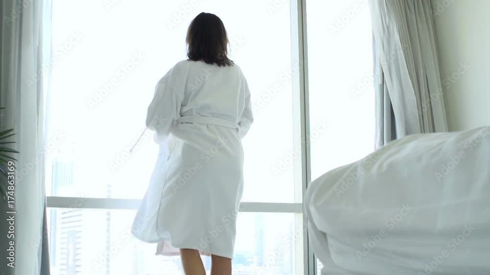 Woman putting on bathrobe by window at home and admire view
Woman putting on bathrobe by window at home and admire view