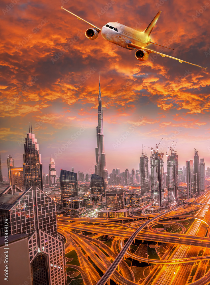 Obraz premium Airplane is flying over Dubai against colorful sunset in United Arab Emirates