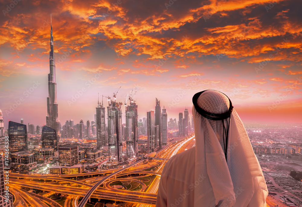 Obraz premium Arabski mężczyzna ogląda panoramę Dubaju z nowoczesną futurystyczną architekturą w Zjednoczonych Emiratach Arabskich.