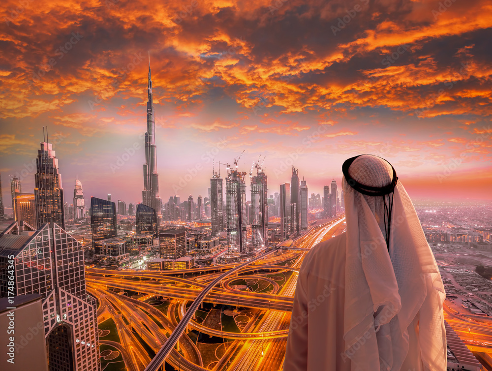 Fototapeta premium Arabian man watching cityscape of Dubai with modern futuristic architecture in United Arab Emirates.