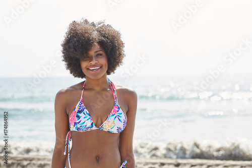 Happy afro american woman in colorful bikini standing on beach