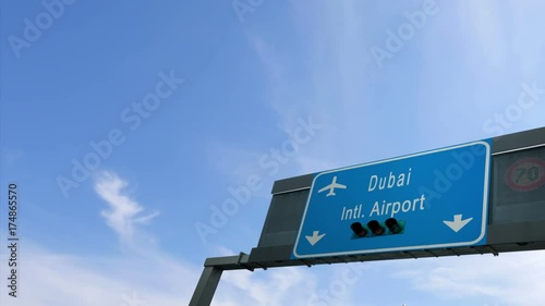 airplane flying over dubai airport signboard photo