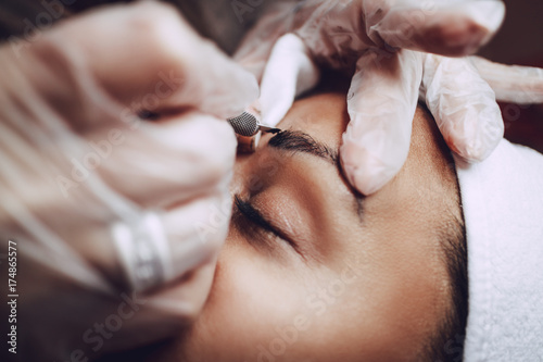 Photo Closeup of a beautician hands applying japanese method of drawing on eyebrows to model