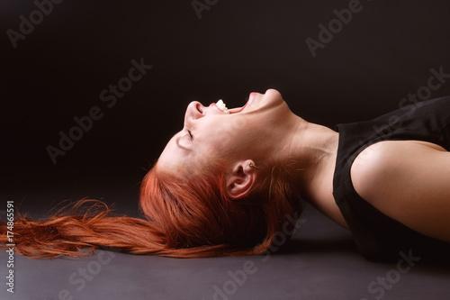 Red-haired woman lying ob the floor and hysterically laughing