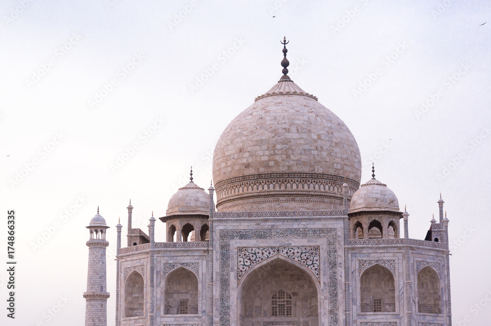 The beautiful Taj Mahal shot during the orange pink sunset light showing the whiteness of the marble and all the details in the minarets and domed roof