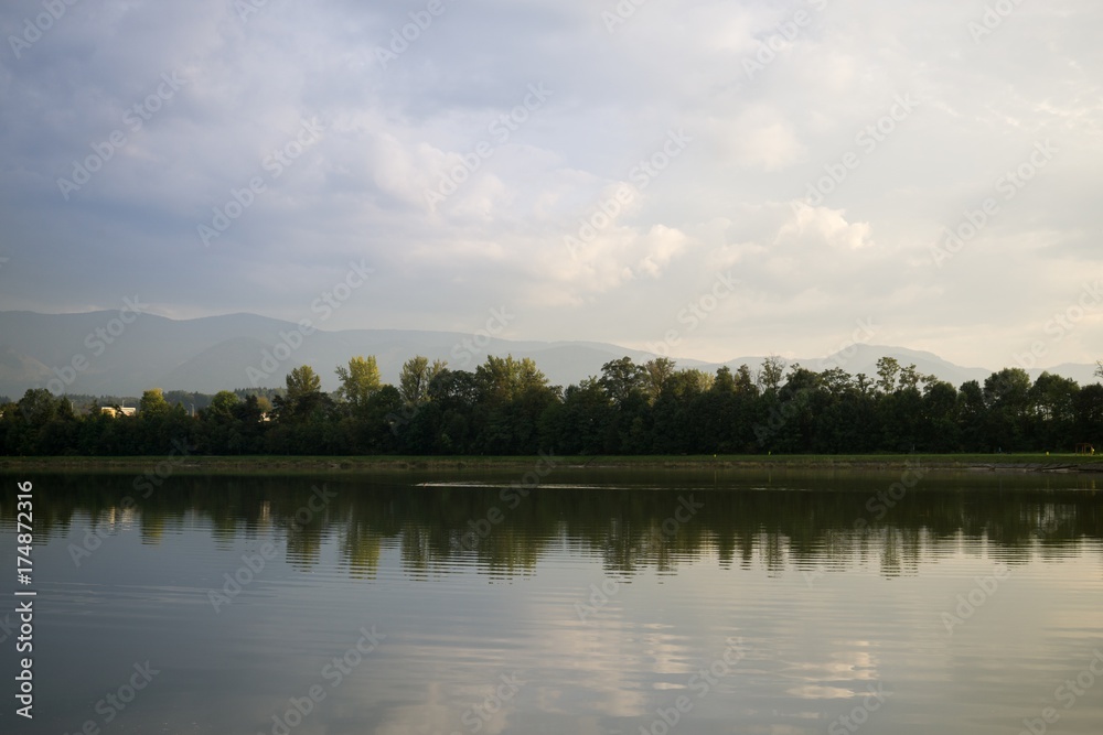 Colorful sunset on the lake with reflections of hills, trees and buildings. Slovakia