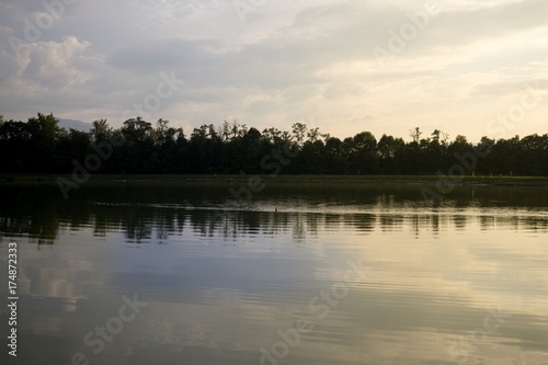 Colorful sunset on the lake with reflections of hills, trees and buildings. Slovakia