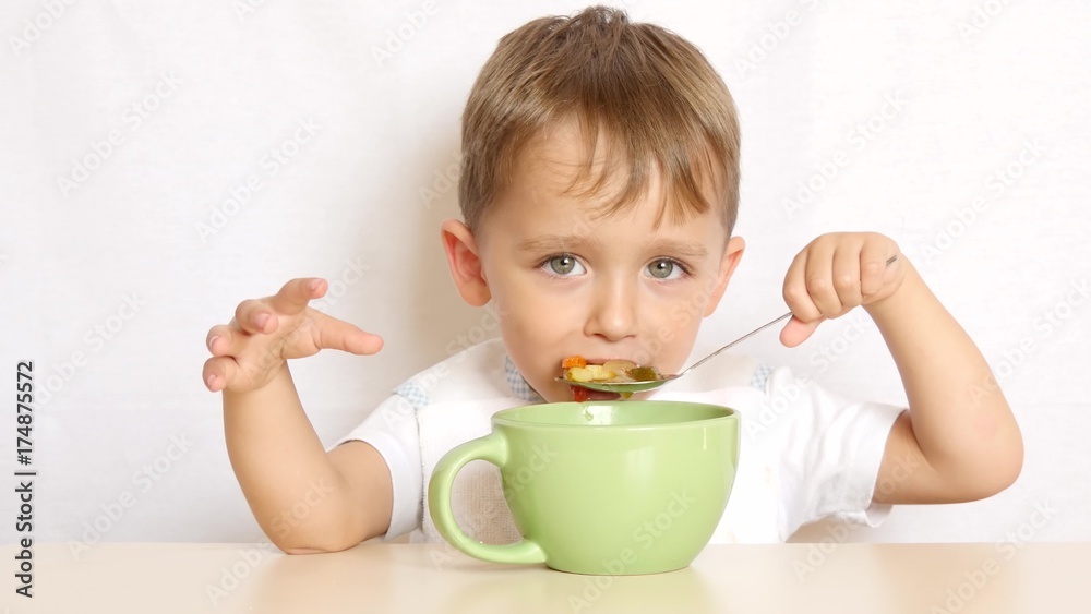 boy eats food with a spoon sitting at the table boy eats food with a spoon sitting at the table