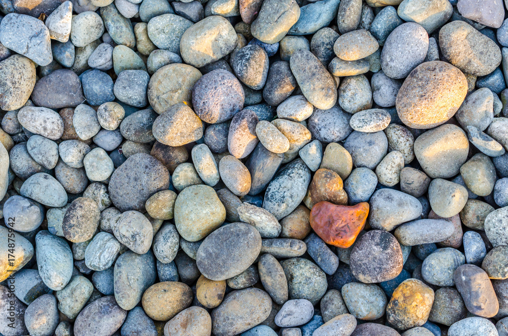 Textured pebble, stone or rock. Abstract background or backdrop. Sunlight streaming onto textured beach or landscape stones.