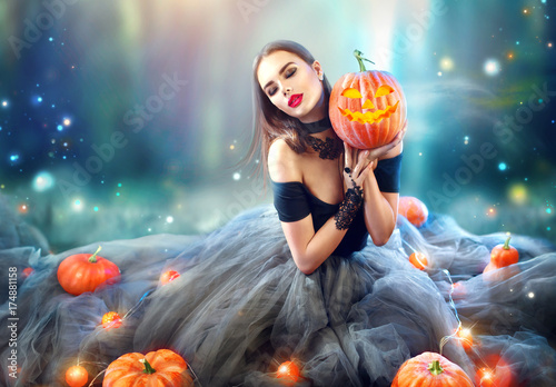 Sexy Halloween witch with curved pumpkins and magic lights