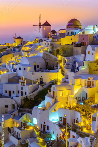 Oia town, Santorini island, Greece at sunset. Traditional and famous white houses and churches with blue domes over the Caldera, Aegean sea.