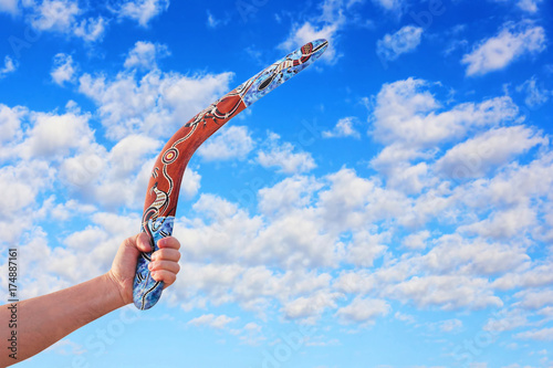 Australian Boomerang in men arm against of cloudy blue sky. photo