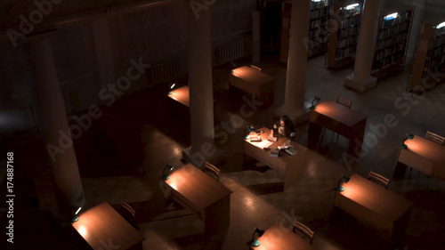 Top view of student hand writing a book with laptop at library. Girl sitting in empty library at night top view photo