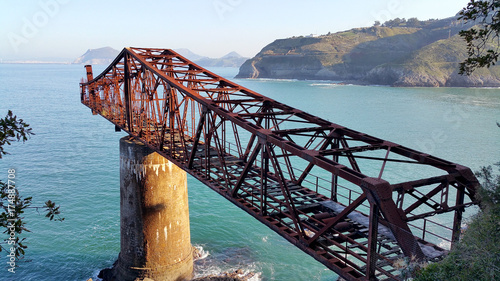 Bridge to nowhere. Abandoned overpass for loading ore from an old mine on the seashore. View from above, against the background of the sea. Miono, Cantabria, North spain.