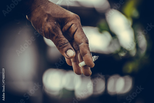 Close up of man hand with cigarette in his fingers on green background. vintage tone. © pookpiik