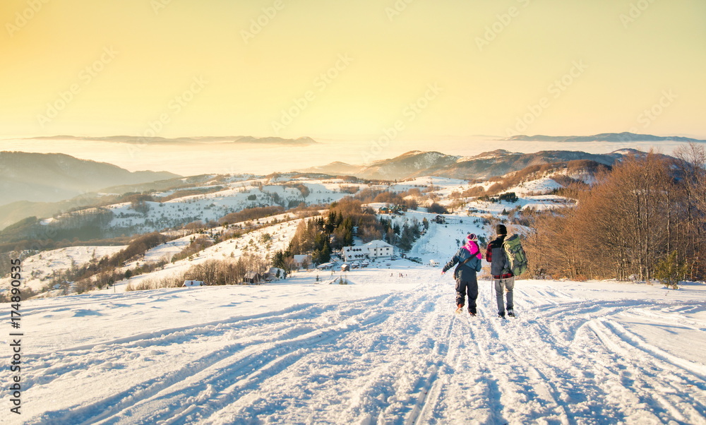 Couple walking down the snowy mountain in sunset time