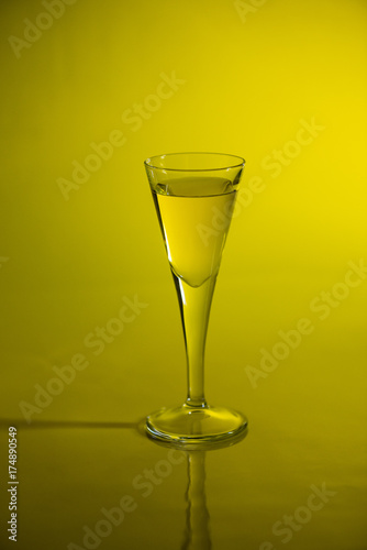 Yellow liquid in aperitif glass on yellow background.