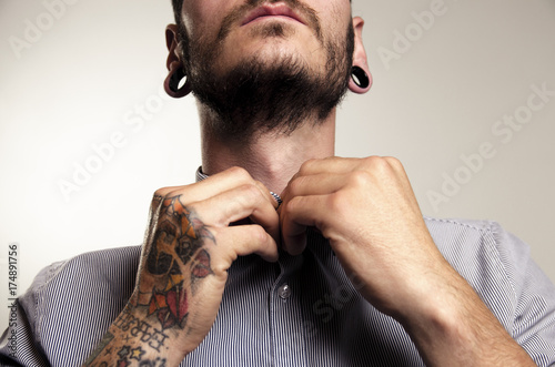 Unrecognizable hipster man with tattoos buttoning shirt  photo