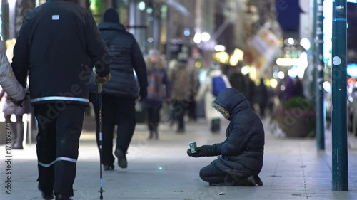 Unidentified homeless man begging on the street of European city winter photo