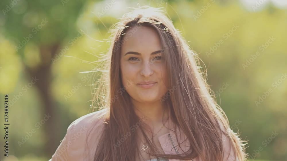Charming young girl posing in the park with a smile on her face. The girl has beautiful long hair. Close-up. Charming young girl posing in the park with a smile on her face. The girl has beautiful long hair. Close-up.