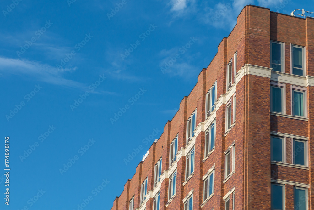 Facade of the brick building against a blue sky with wispy clouds
