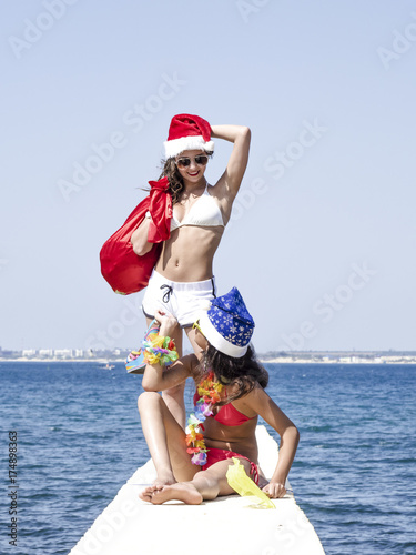 Two girlfriends in santa hat during beach vacation