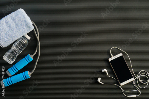 Fitness concept. Top view of fitness equipment on black yoga mat background.