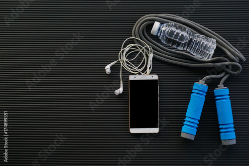 Fitness concept. Top view of fitness equipment on black yoga mat background.