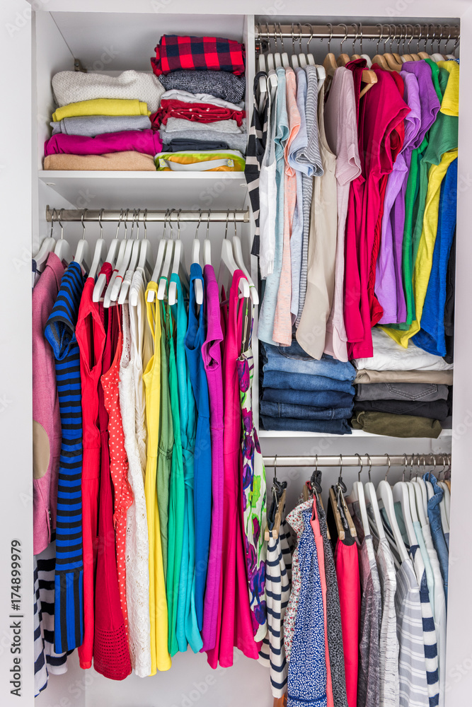 Home closet organized walk-in bedroom wardrobe of women fashion clothes  hanging on racks. Summer style, dresses and t-shirts Stock Photo