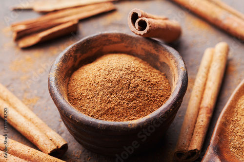 Whole cinnamon sticks and powder on brown rustic background. Aromatic spices.